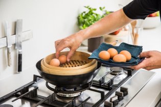 Placing eggs in a bamboo steamer
