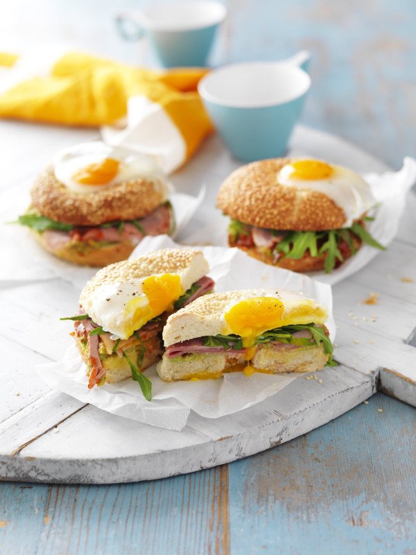 Bagels filled with rocket, ham and topped with an oozing fried egg