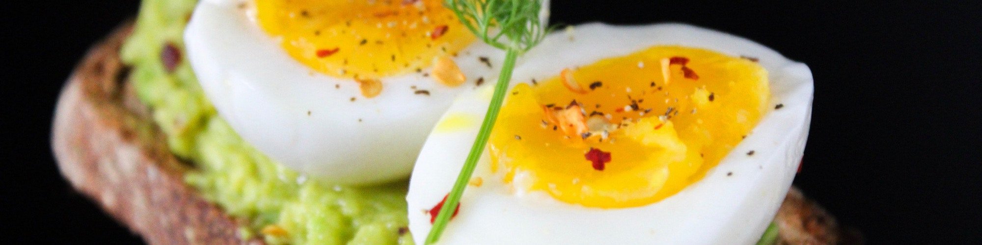 sliced egg on top of green salad with bread 824635