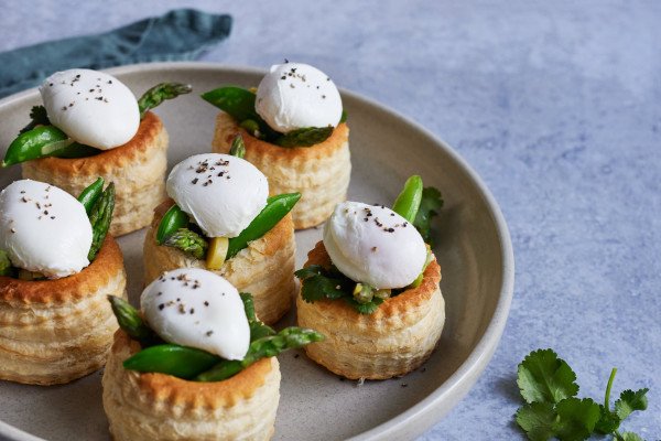 a plate of 6 veggie tarts with poached egg on top of each